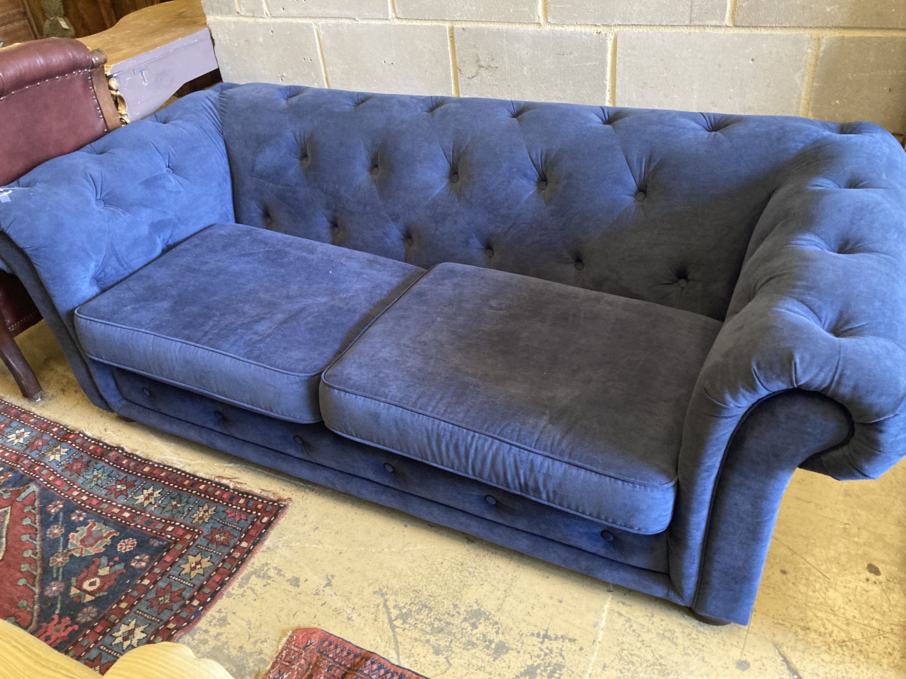 A pair of Chesterfield style settees upholstered in blue dralon and a footstool, largest length 210cm, depth 96cm, height 74cm